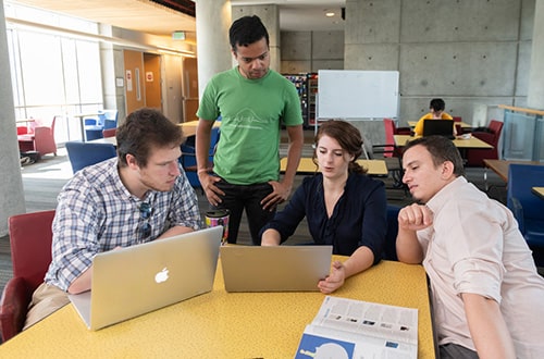 Graduate students looking at laptop together